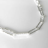 Close-up of the hammered links of the silver paperclip chain necklace, reflecting detailed craftmanship.