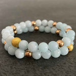 Set of two stacked aquamarine bead bracelets with gold accents.