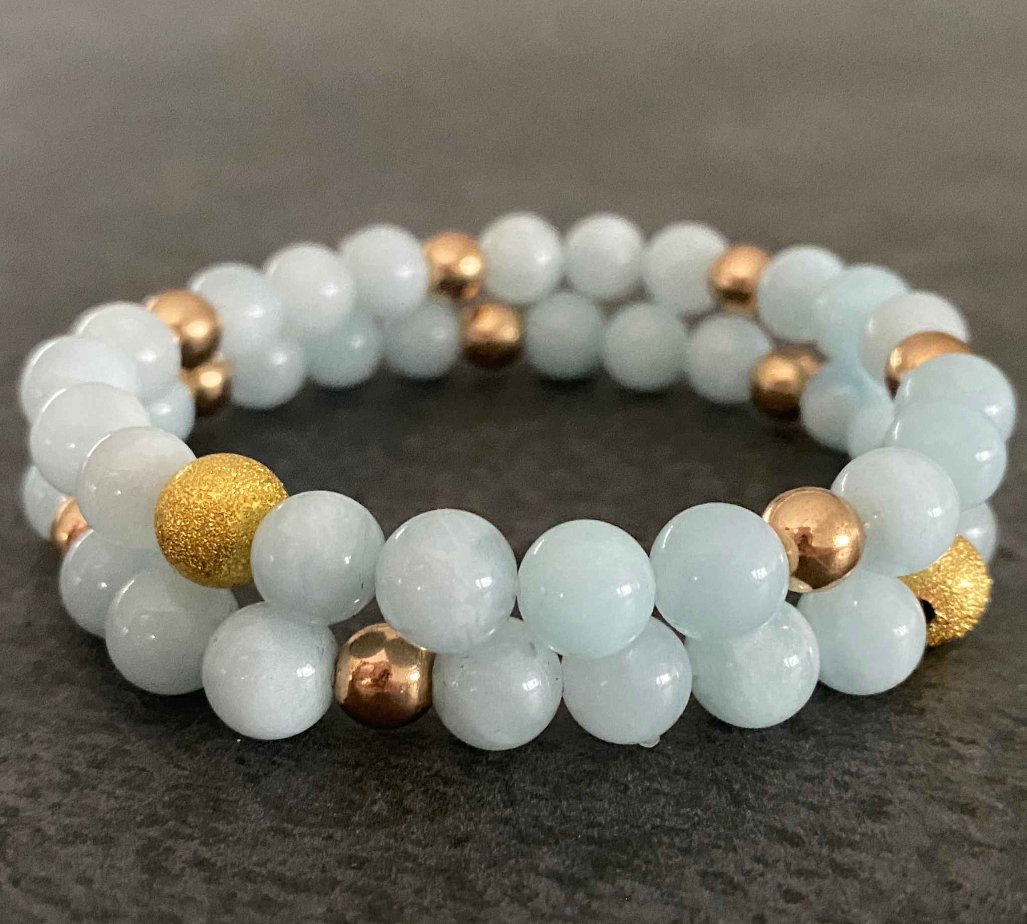 Set of two stacked aquamarine bead bracelets with gold accents.