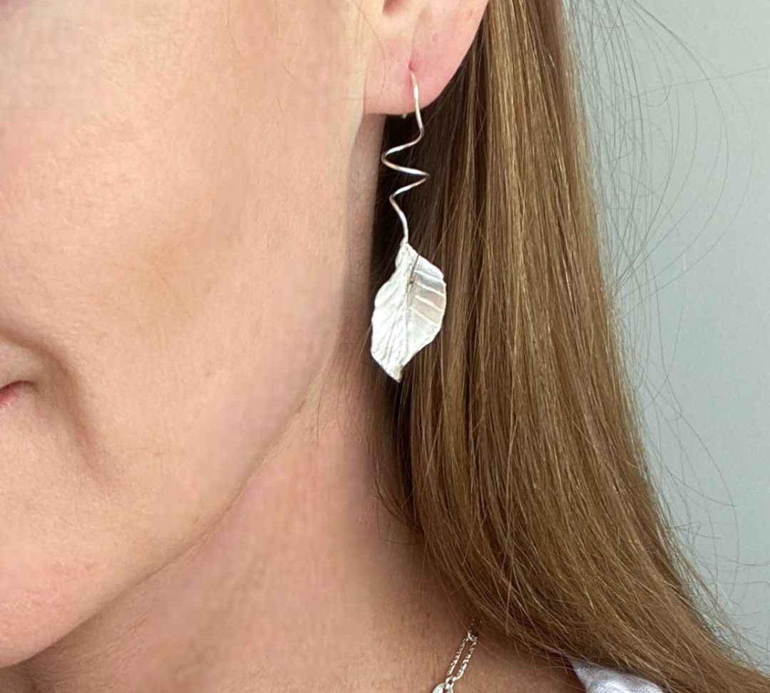 Close-up view of vintage-inspired leaf drop earrings in sterling silver, showcasing intricate craftsmanship.