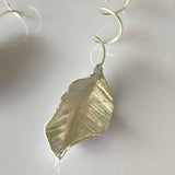 Earthy and elegant sterling silver leaf dangle earrings presented by Alessandra James.