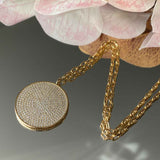 Detailed view of the exquisite medallion pendant in gold, showcasing the intricate placement of sparkling diamonettes.