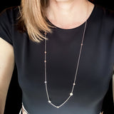 A closeup of the timeless Pebble Necklace in rose gold, worn with a black dress. 