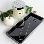 Styled view of Pebble Necklace in Silver, styled against a black display alongside a silver ring.