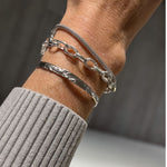 A closeup of the Silver Foil Textured Bangle worn on a wrist, along with two other silver bracelets.