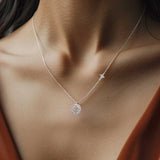 A closeup of a woman in a brown dress wearing a silver celestial medallion necklace.